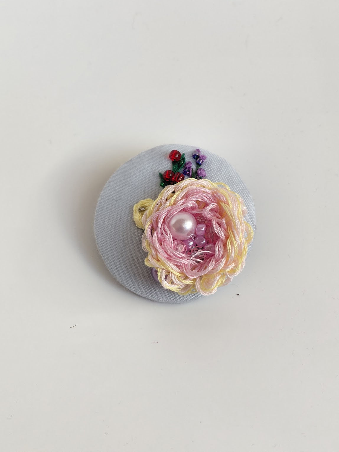 Decorative burgundy flower brooch on light blue background