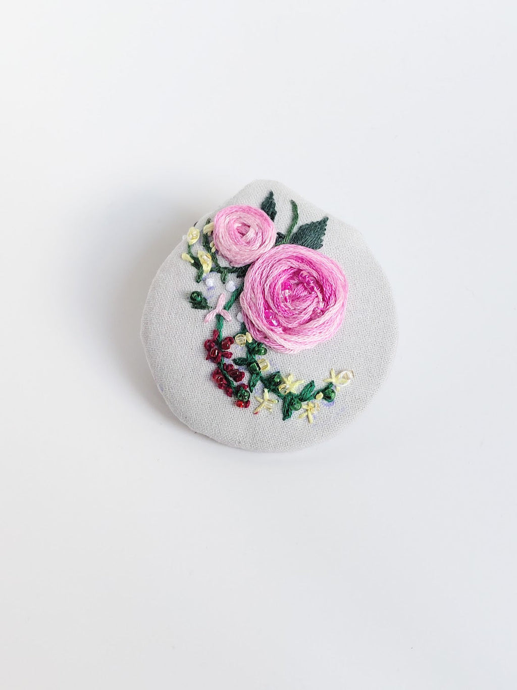 Decorative burgundy flower brooch on grey  background