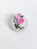 Decorative burgundy flower brooch on grey  background