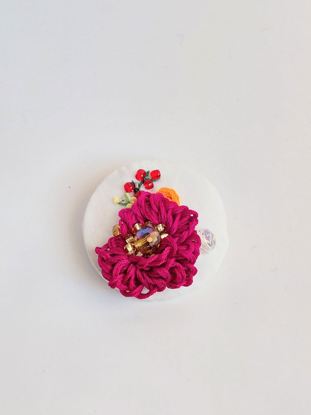 Decorative burgundy flower brooch on white background
