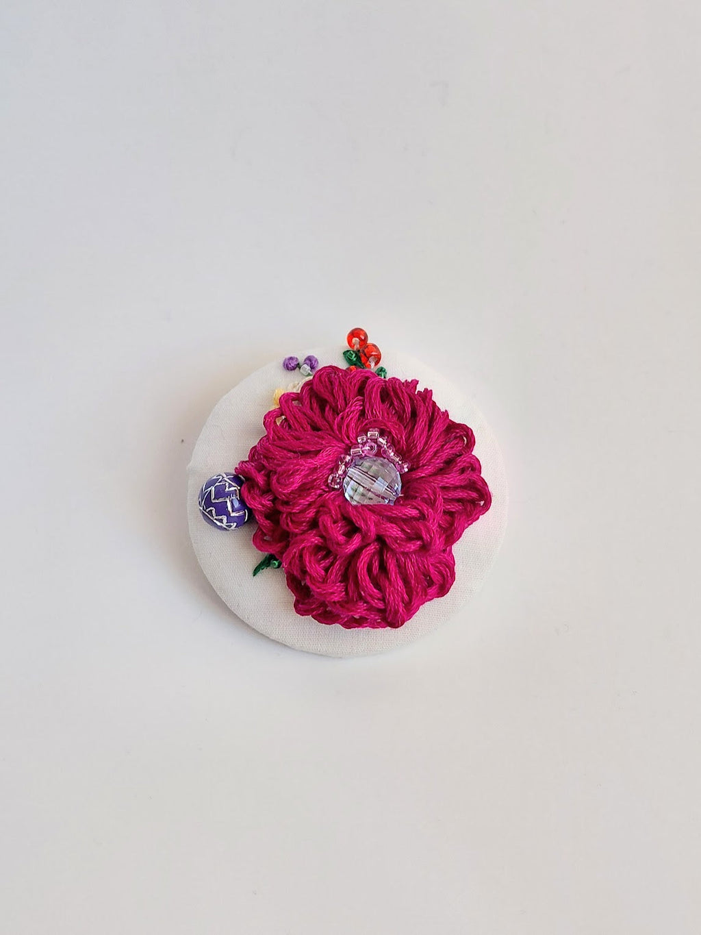 Decorative burgundy flower brooch on white background