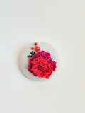 Decorative burgundy flower brooch on grey background