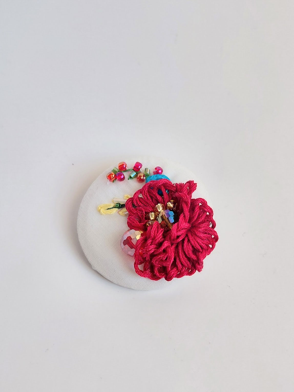 Decorative burgundy flower brooch on white background