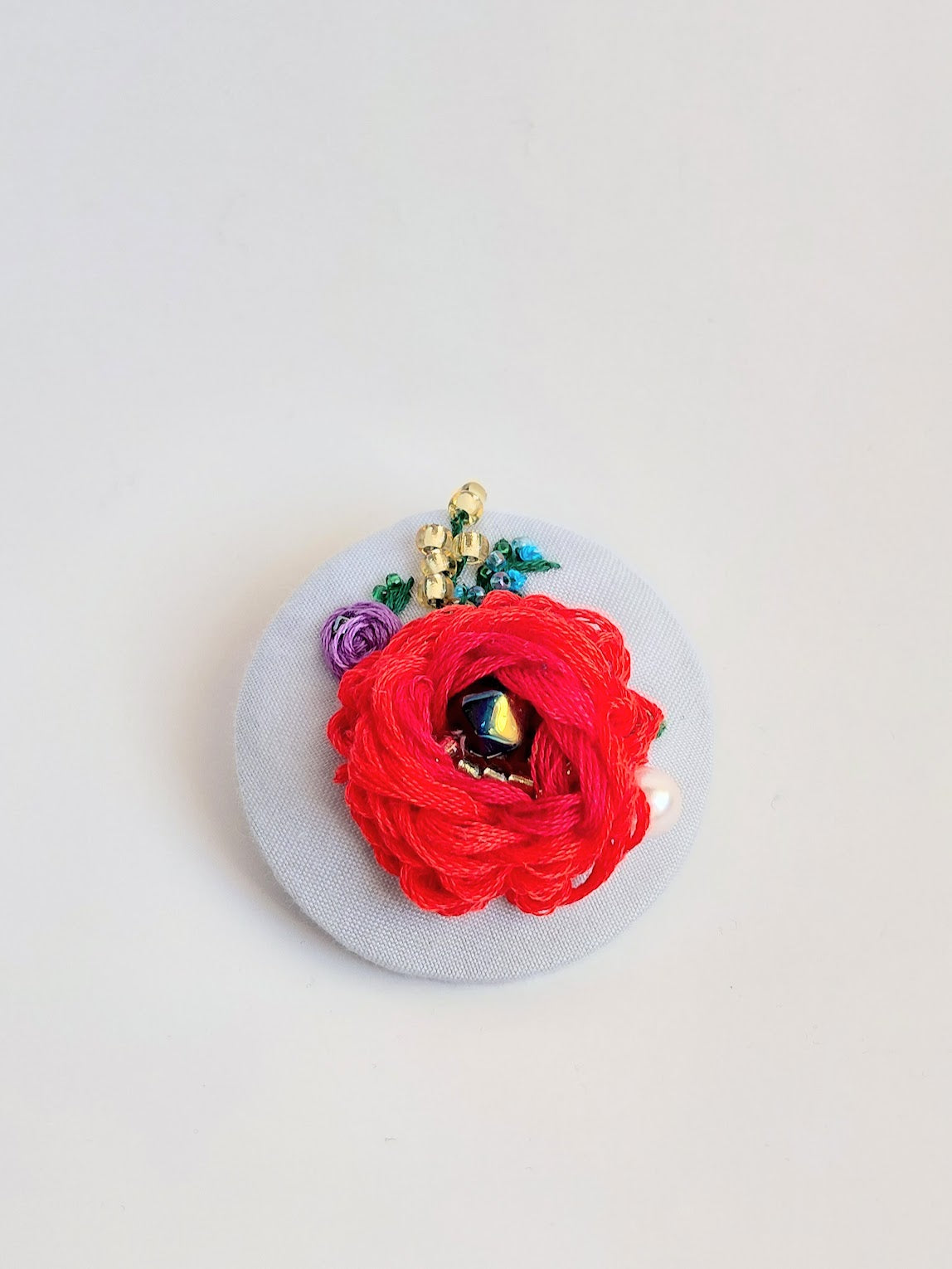 Decorative red flower brooch on light blue background