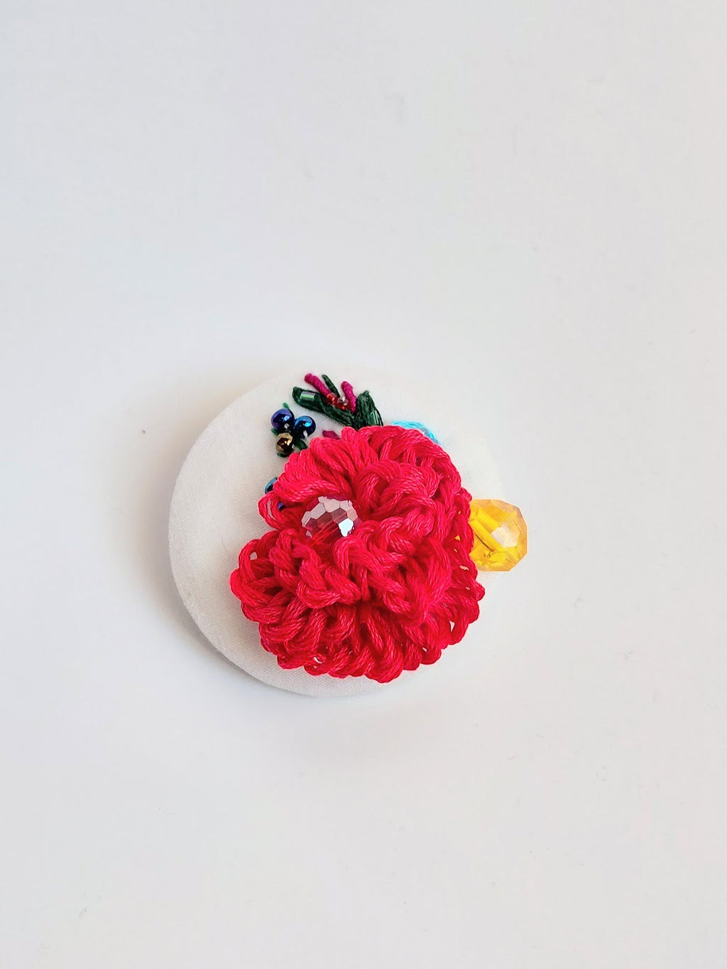 Decorative red flower brooch on white background