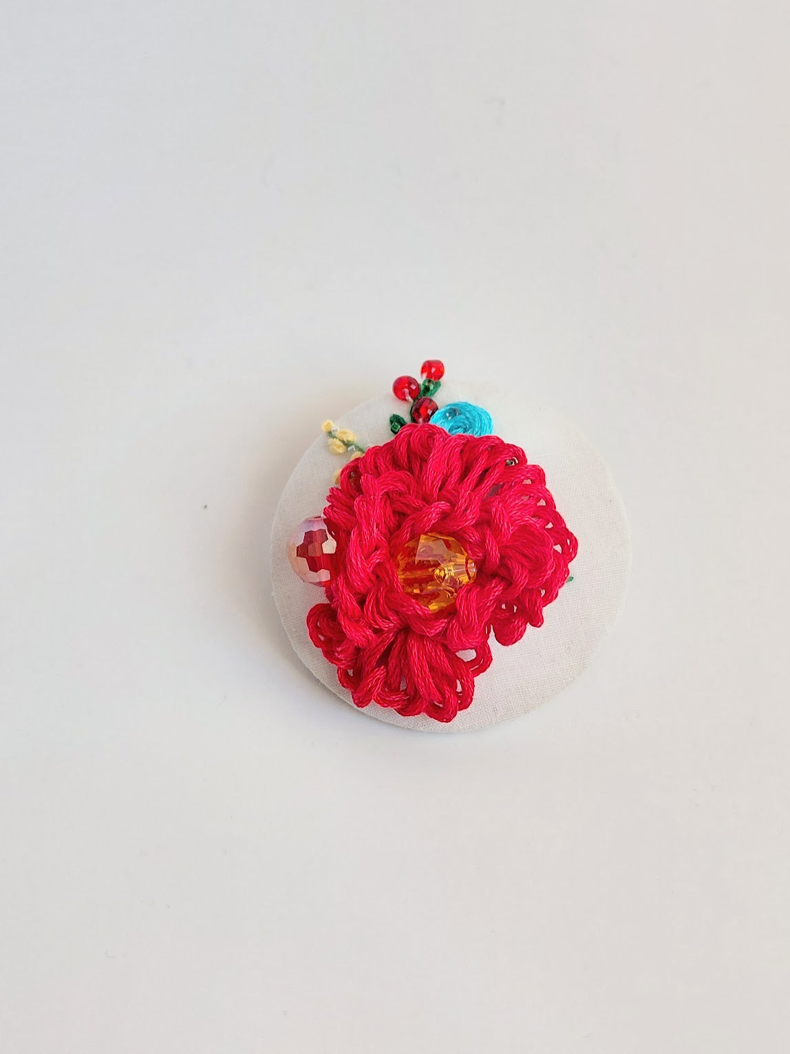 Decorative red flower brooch on white background