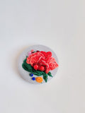 Decorative red flower brooch on light blue background