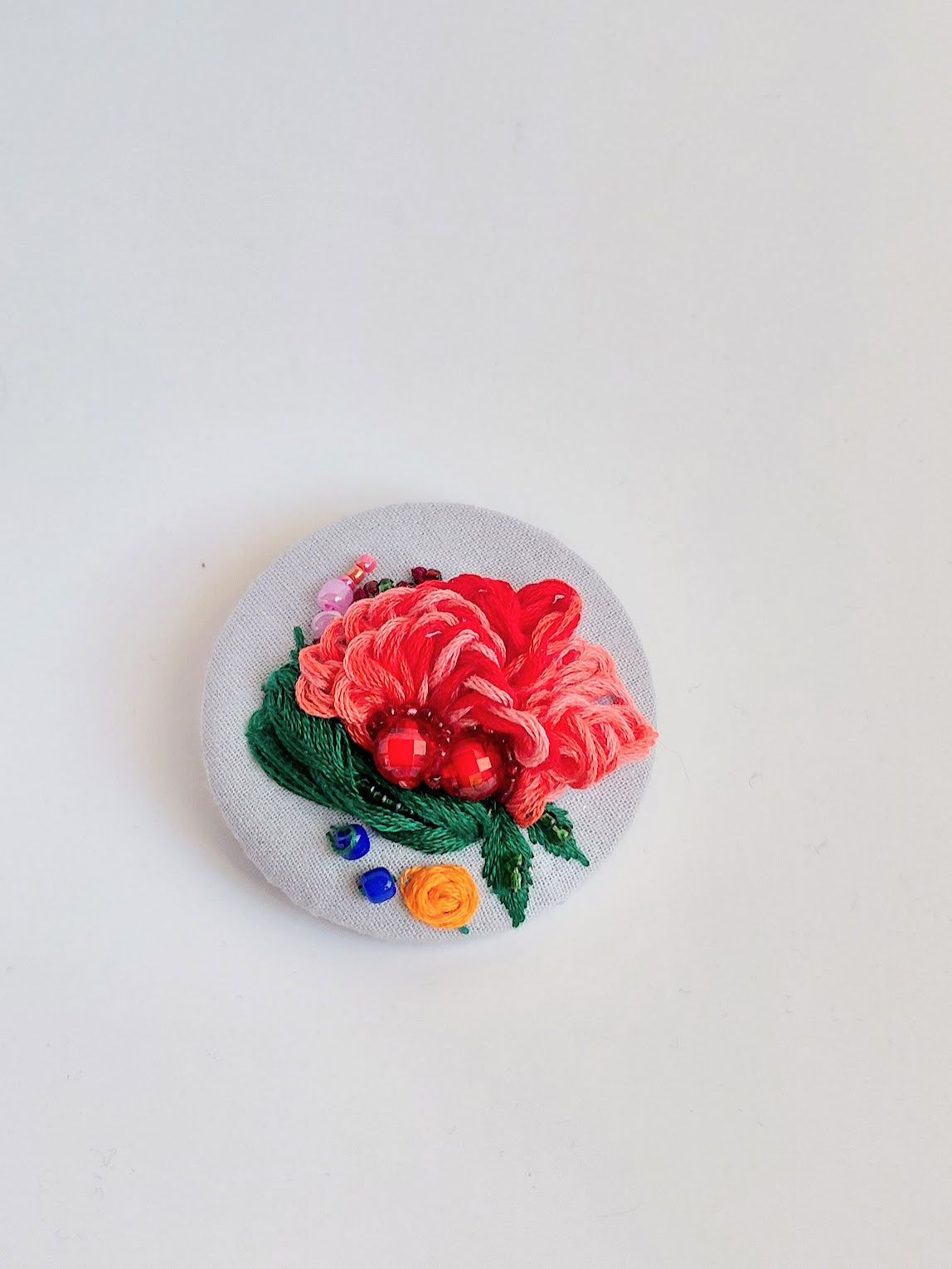 Decorative red flower brooch on light blue background
