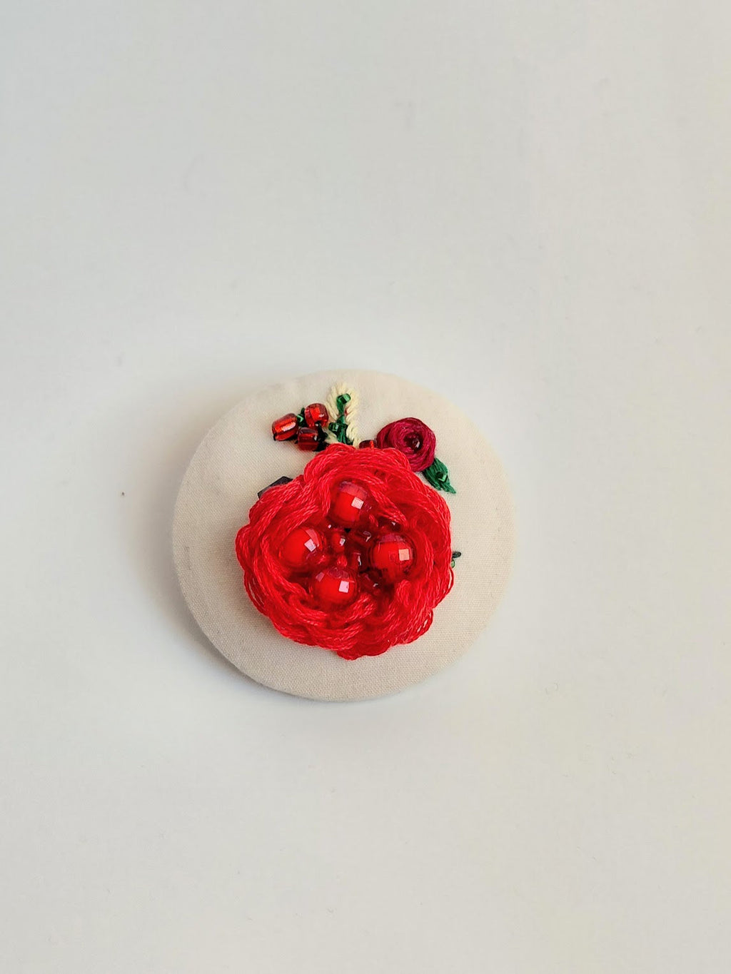 Decorative red flower brooch on cream background
