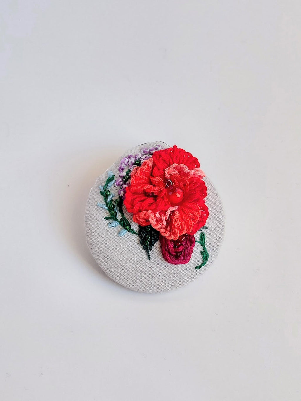 Decorative red flower brooch on grey background