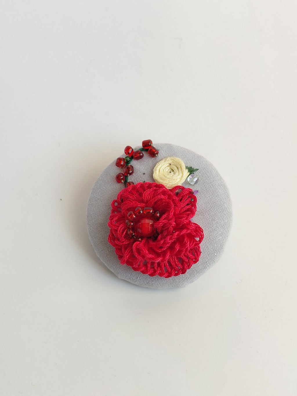 Decorative red flower brooch on grey background