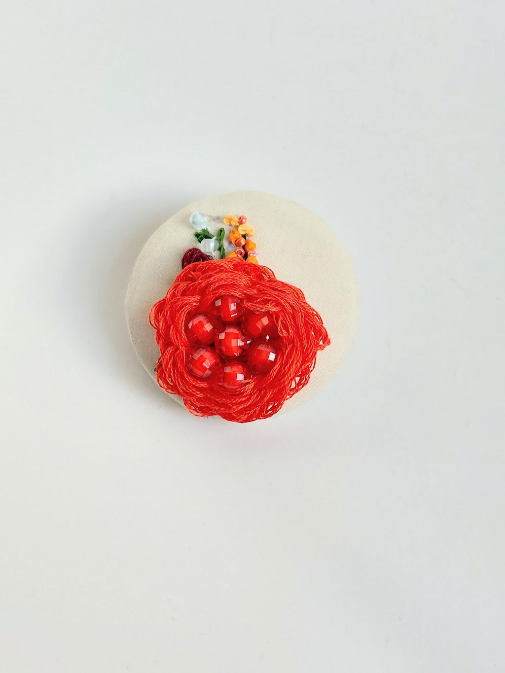 Decorative red flower brooch on cream background