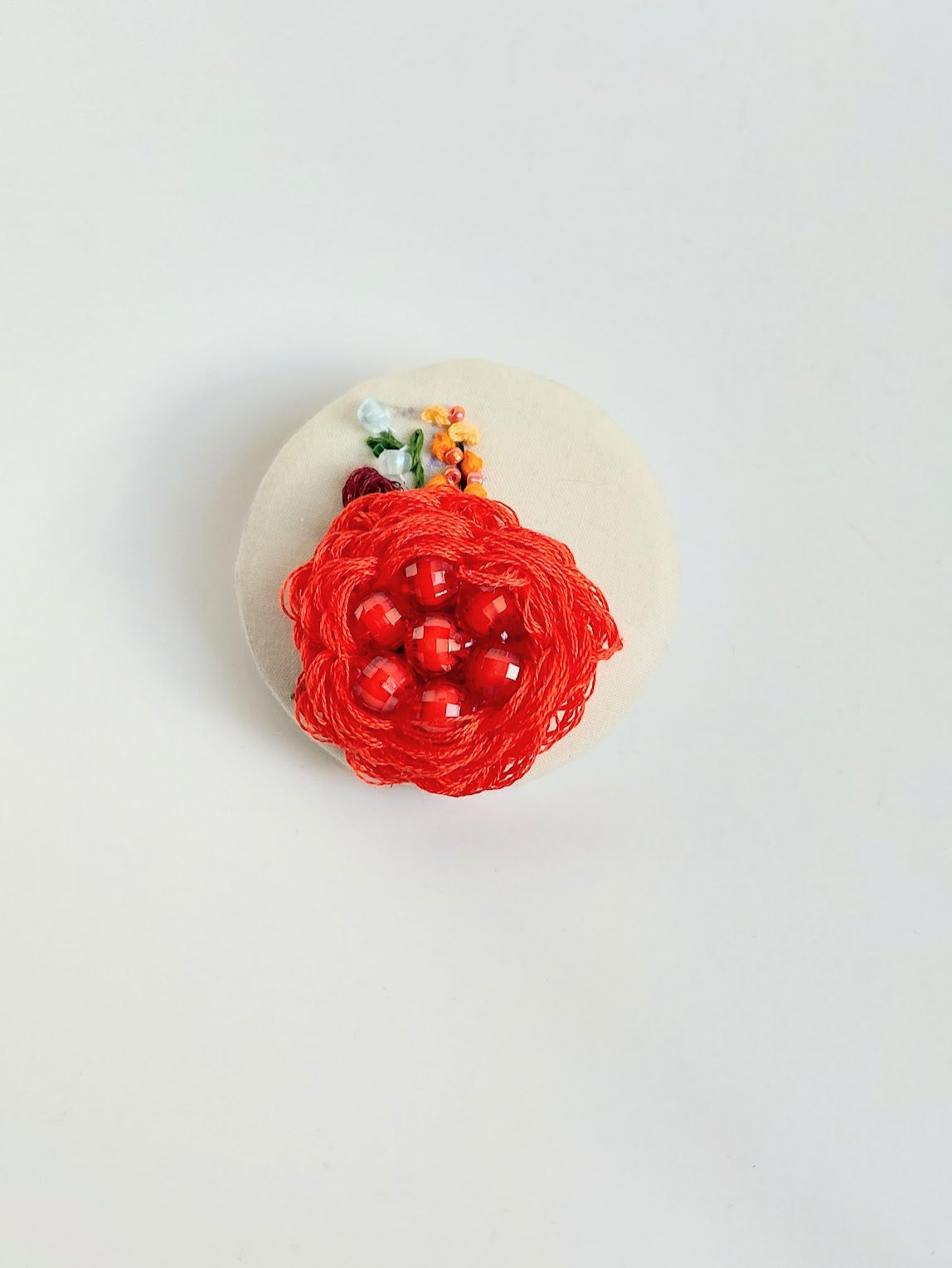 Decorative red flower brooch on cream background