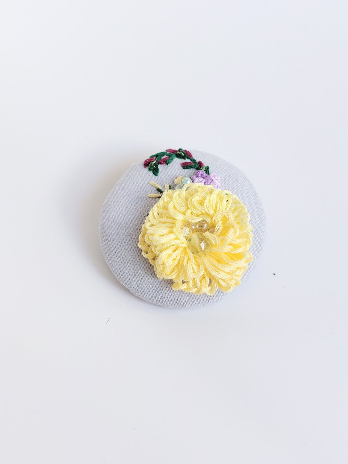 Decorative yellow flower brooch on light blue background