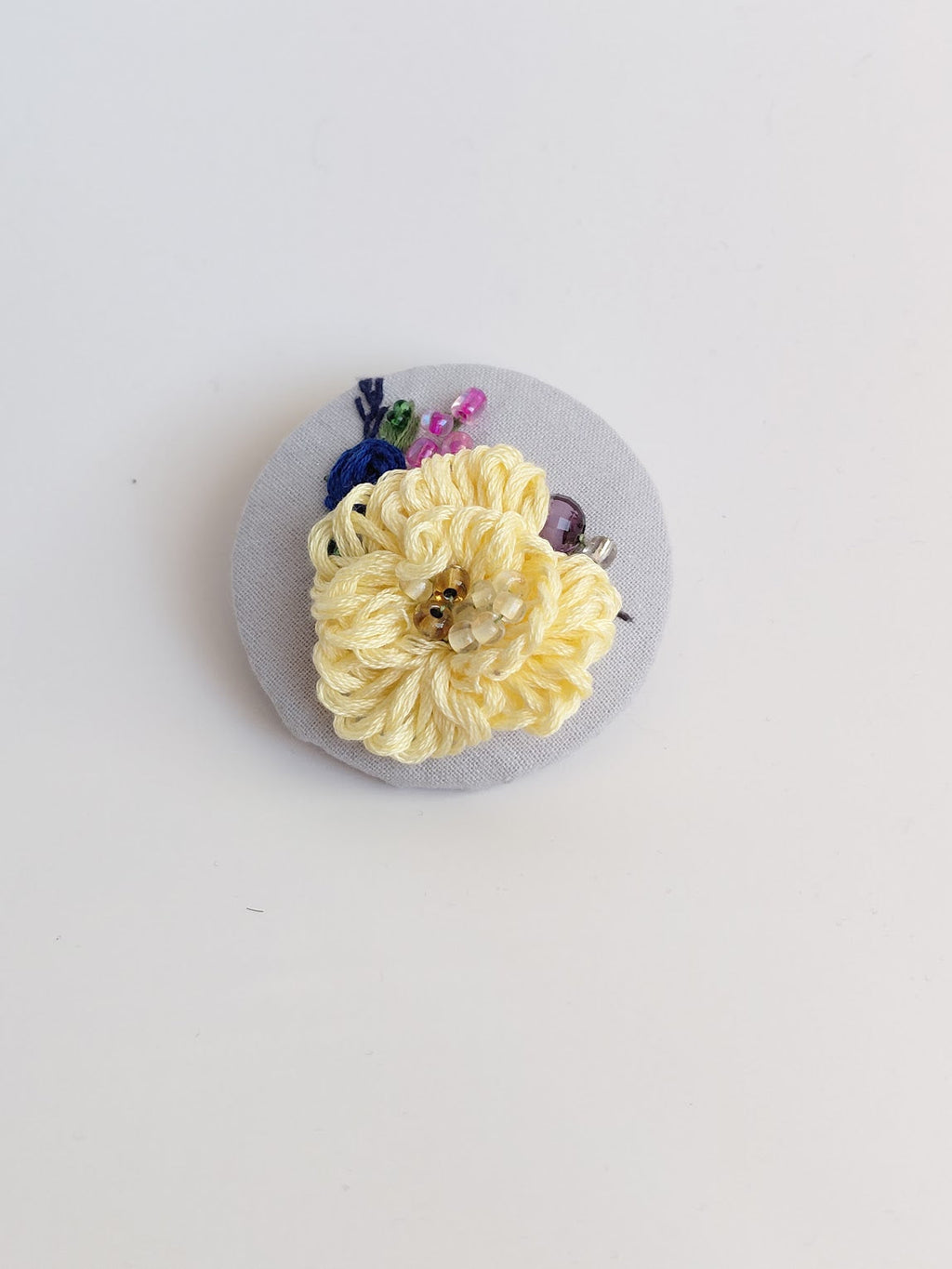 Decorative yellow flower brooch on light blue background