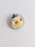 Decorative yellow flower brooch on light blue background