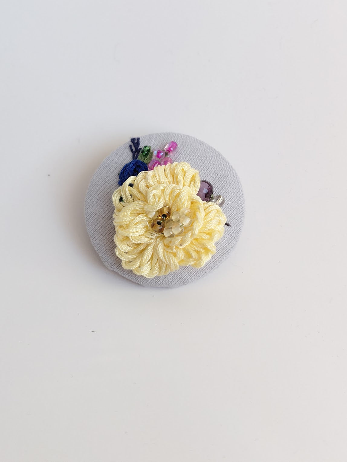 Decorative yellow flower brooch on light blue background