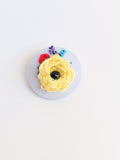 Decorative yellow flower brooch on light blue background