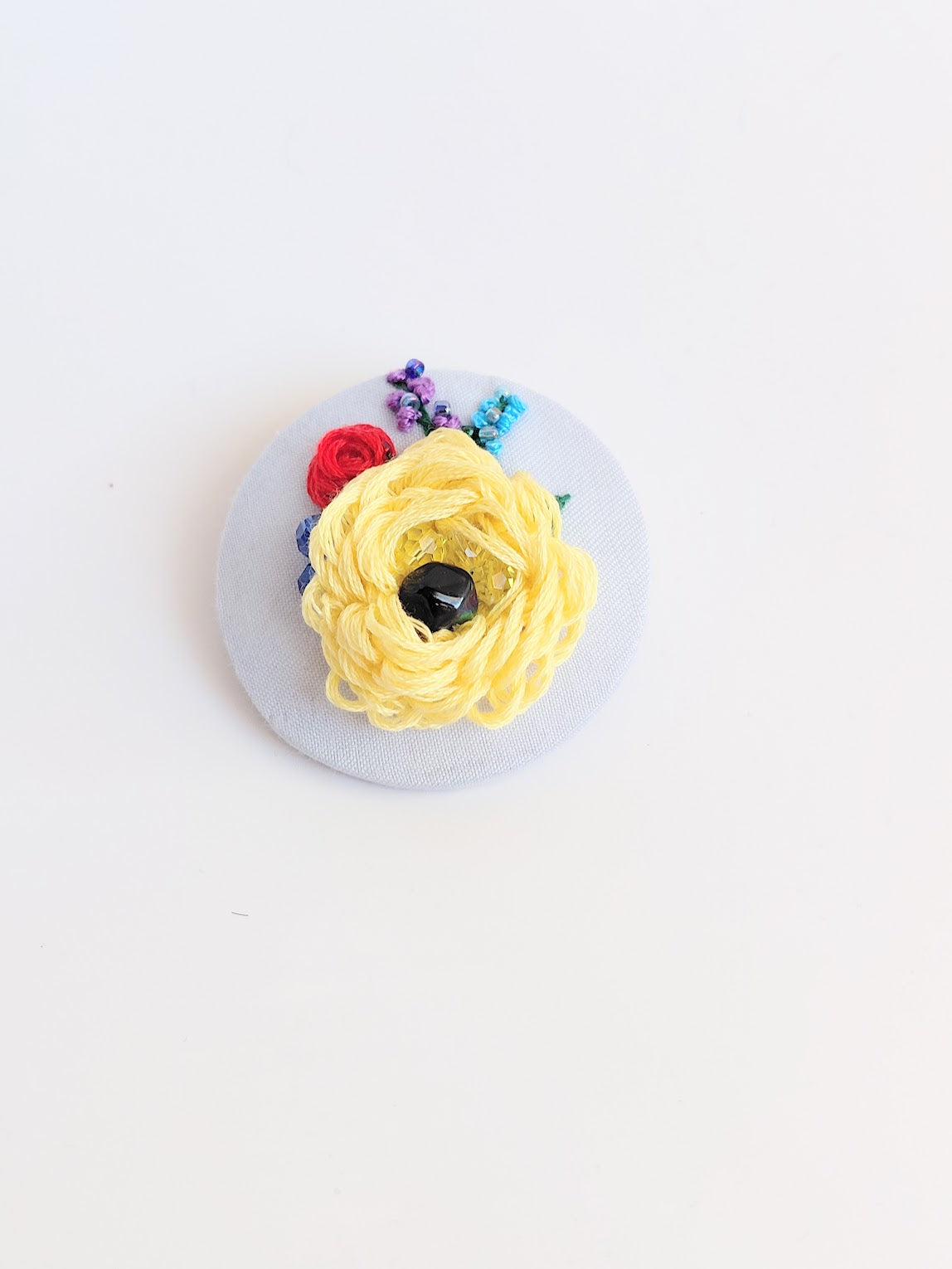 Decorative yellow flower brooch on light blue background