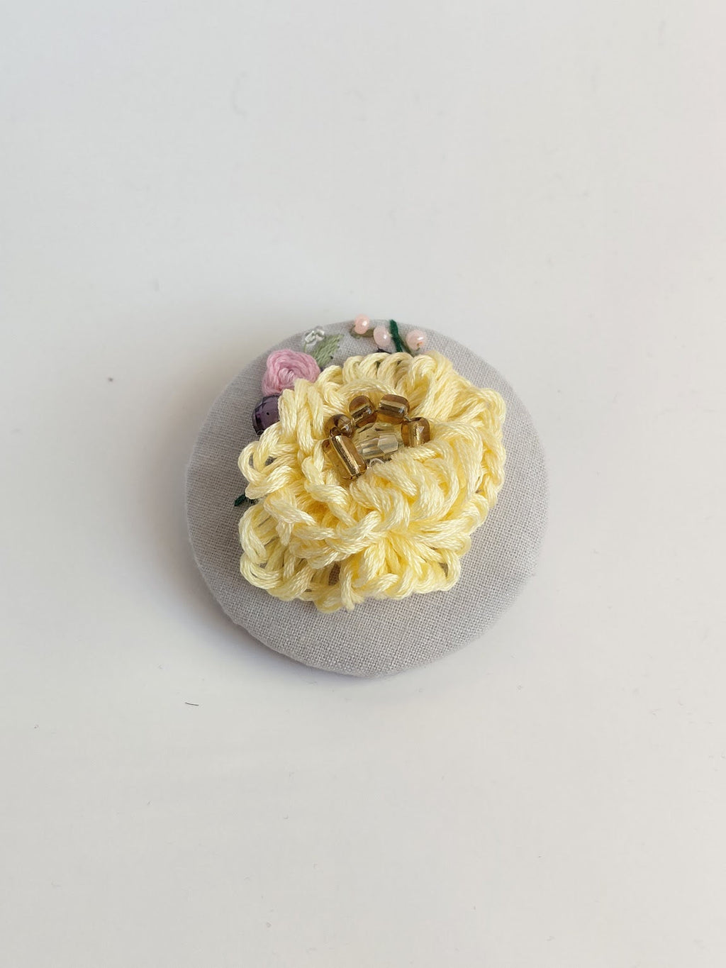 Decorative yellow flower brooch on grey background