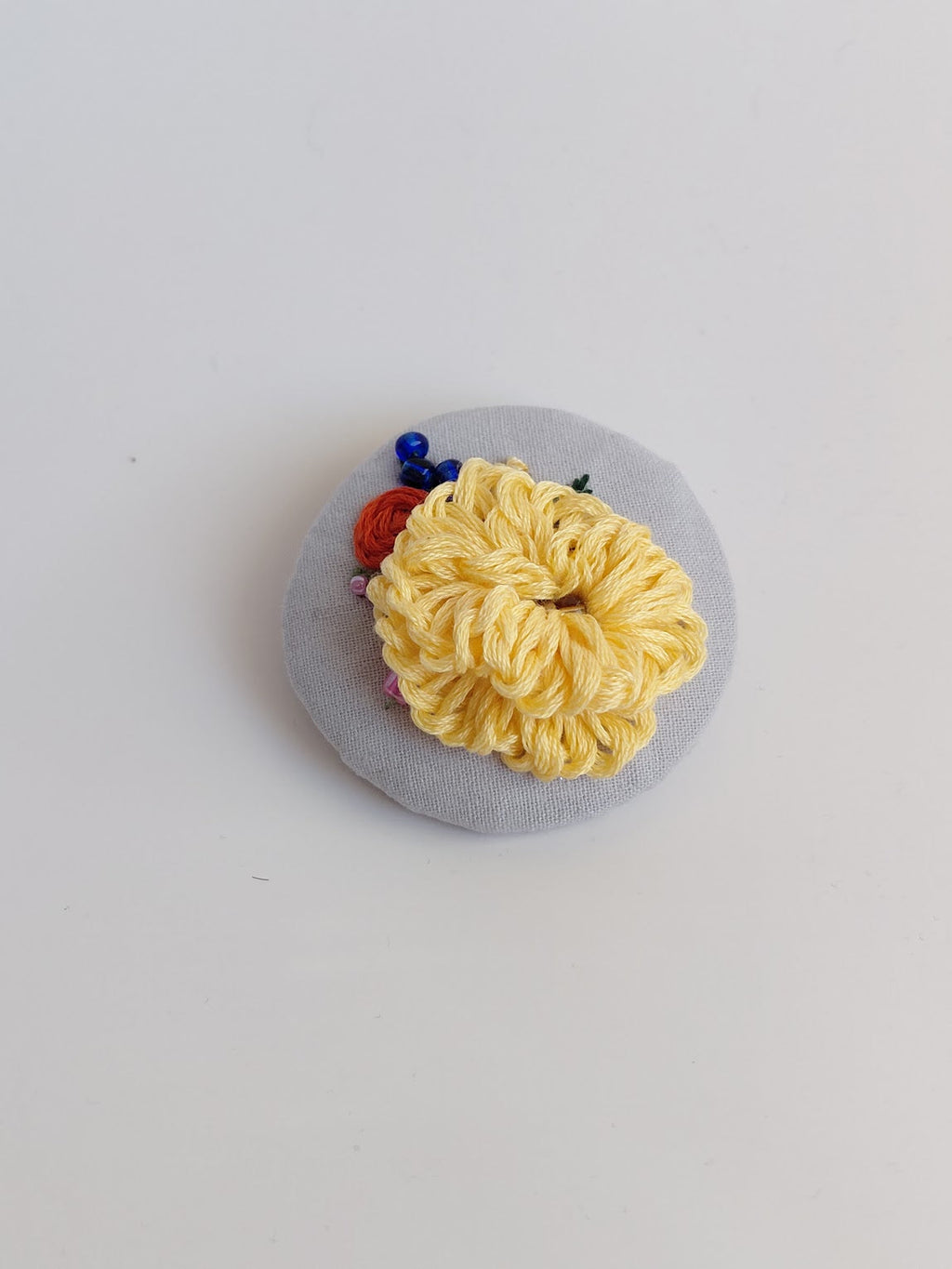 Decorative yellow flower brooch on grey background
