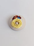 Decorative yellow flower brooch on cream background