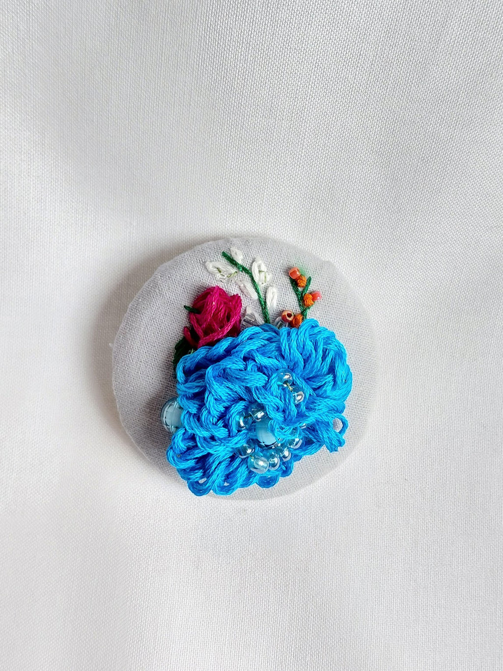 Decorative turquoise flower brooch on blue spec background