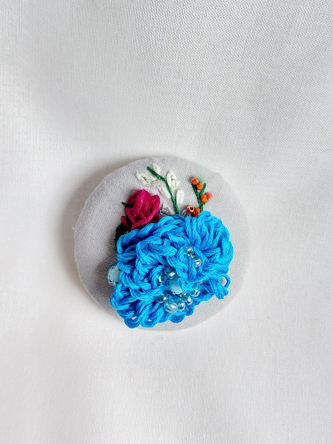 Decorative turquoise flower brooch on blue spec background