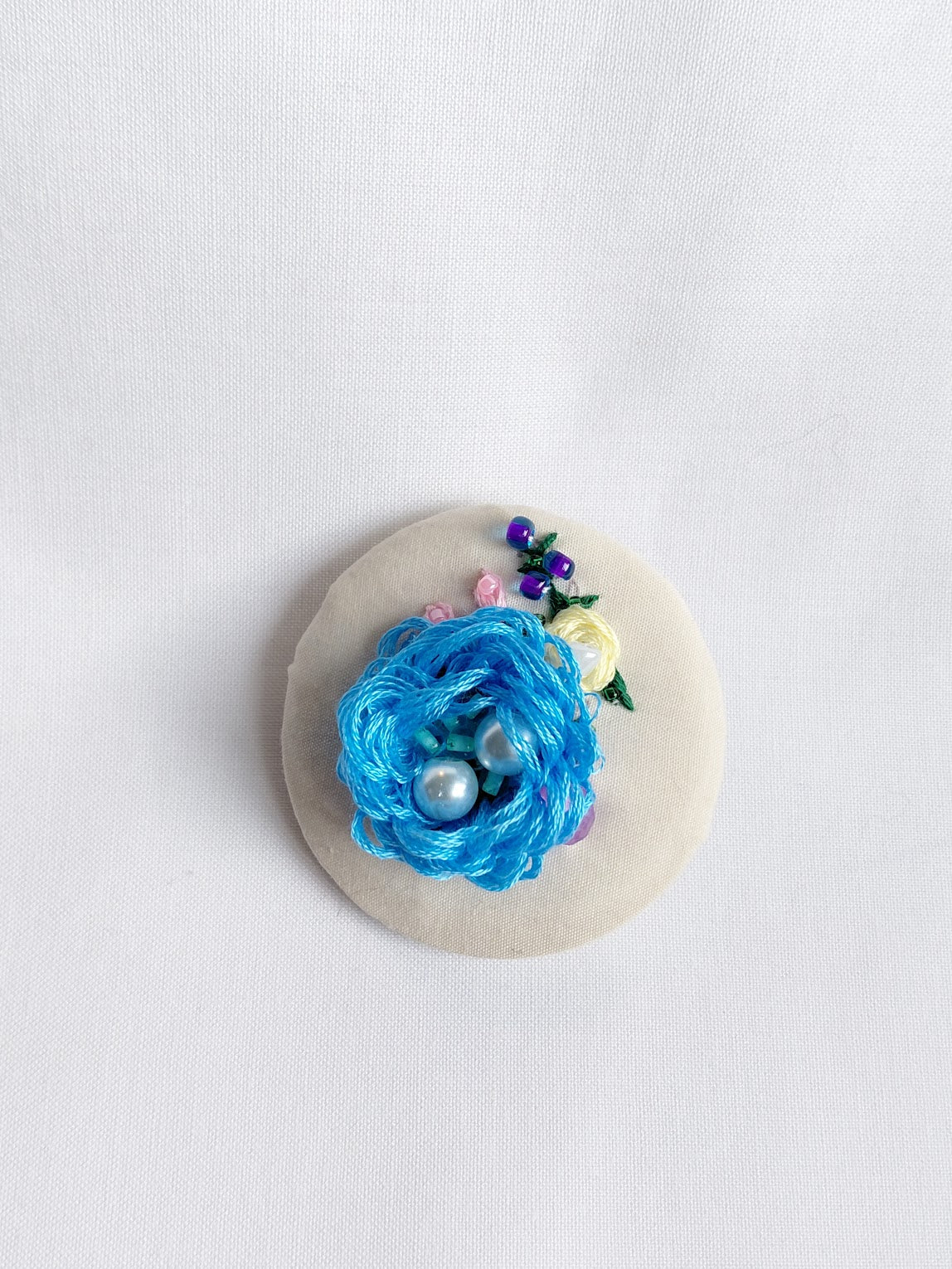 Decorative blue flower brooch on cream background