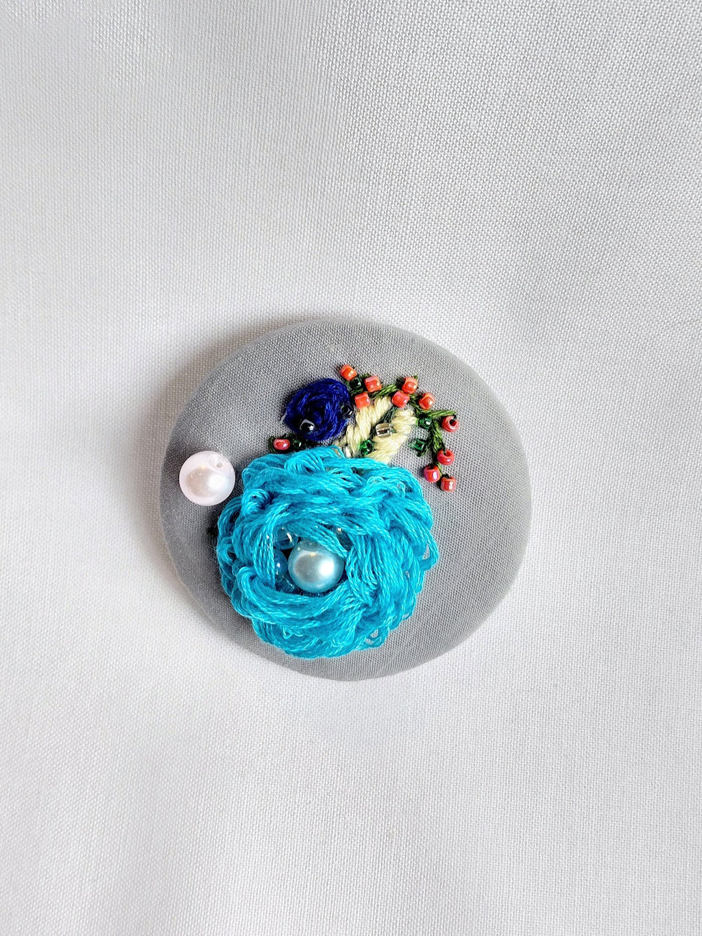 Decorative turquoise flower brooch on grey  background