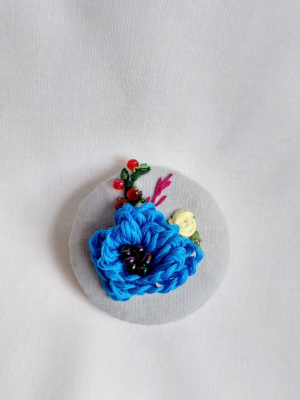 Decorative turquoise flower brooch on blue spec background