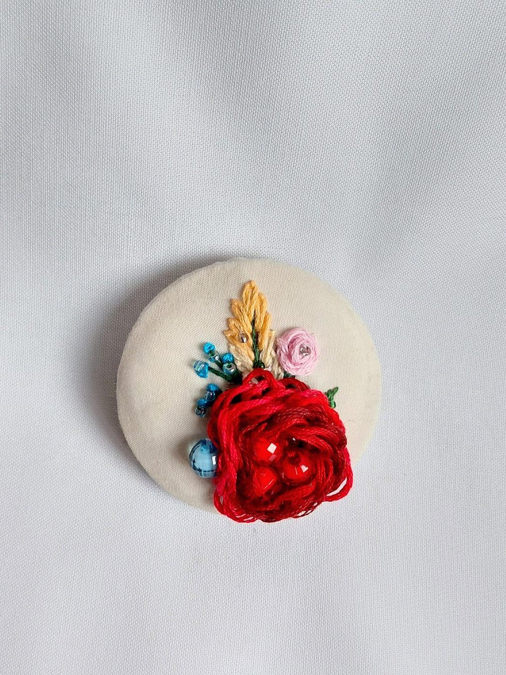 Decorative burgundy flower brooch on cream background