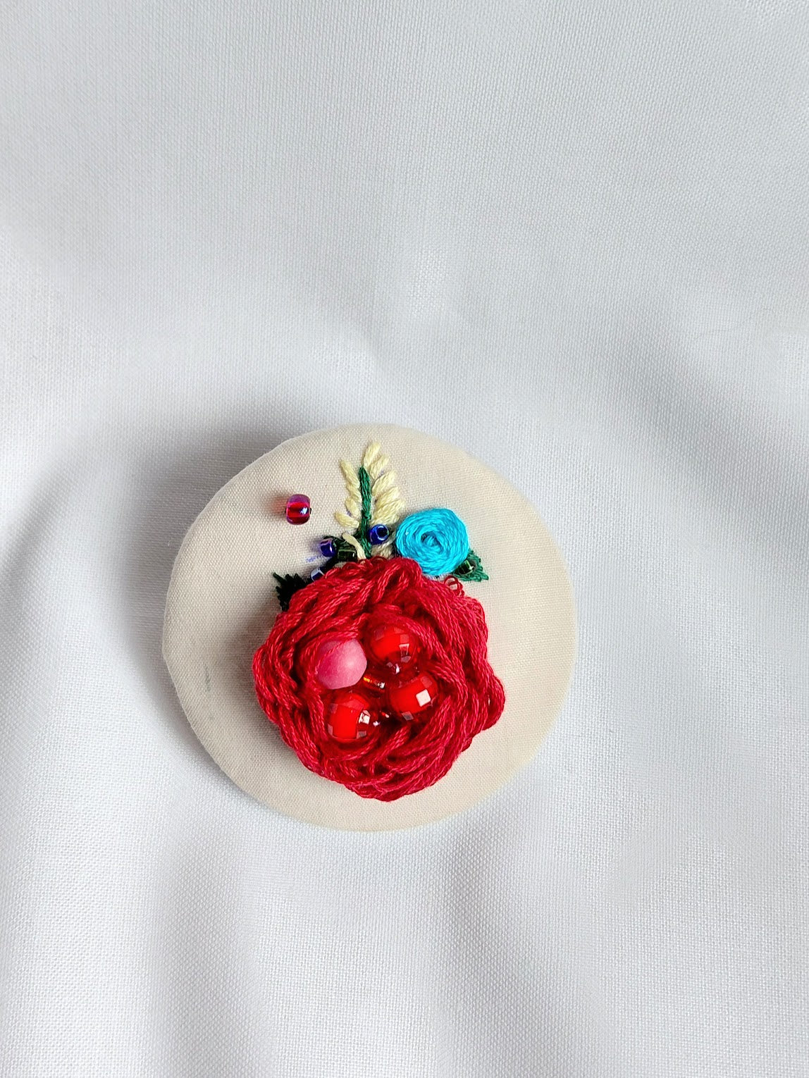 Decorative burgundy flower brooch on cream background