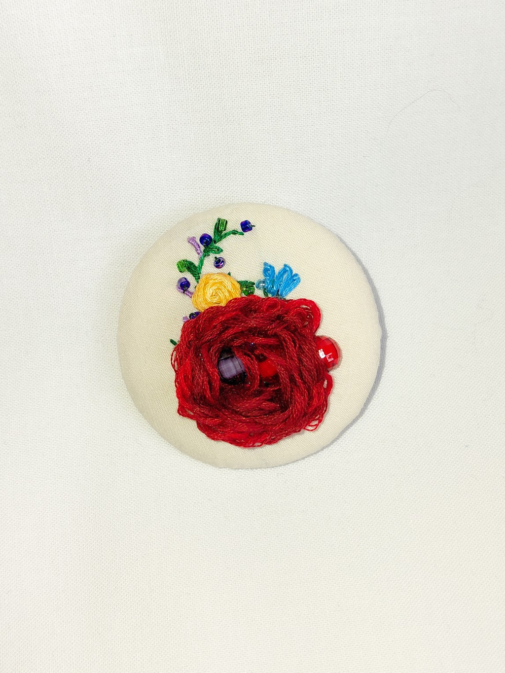 Decorative burgundy flower brooch on cream background