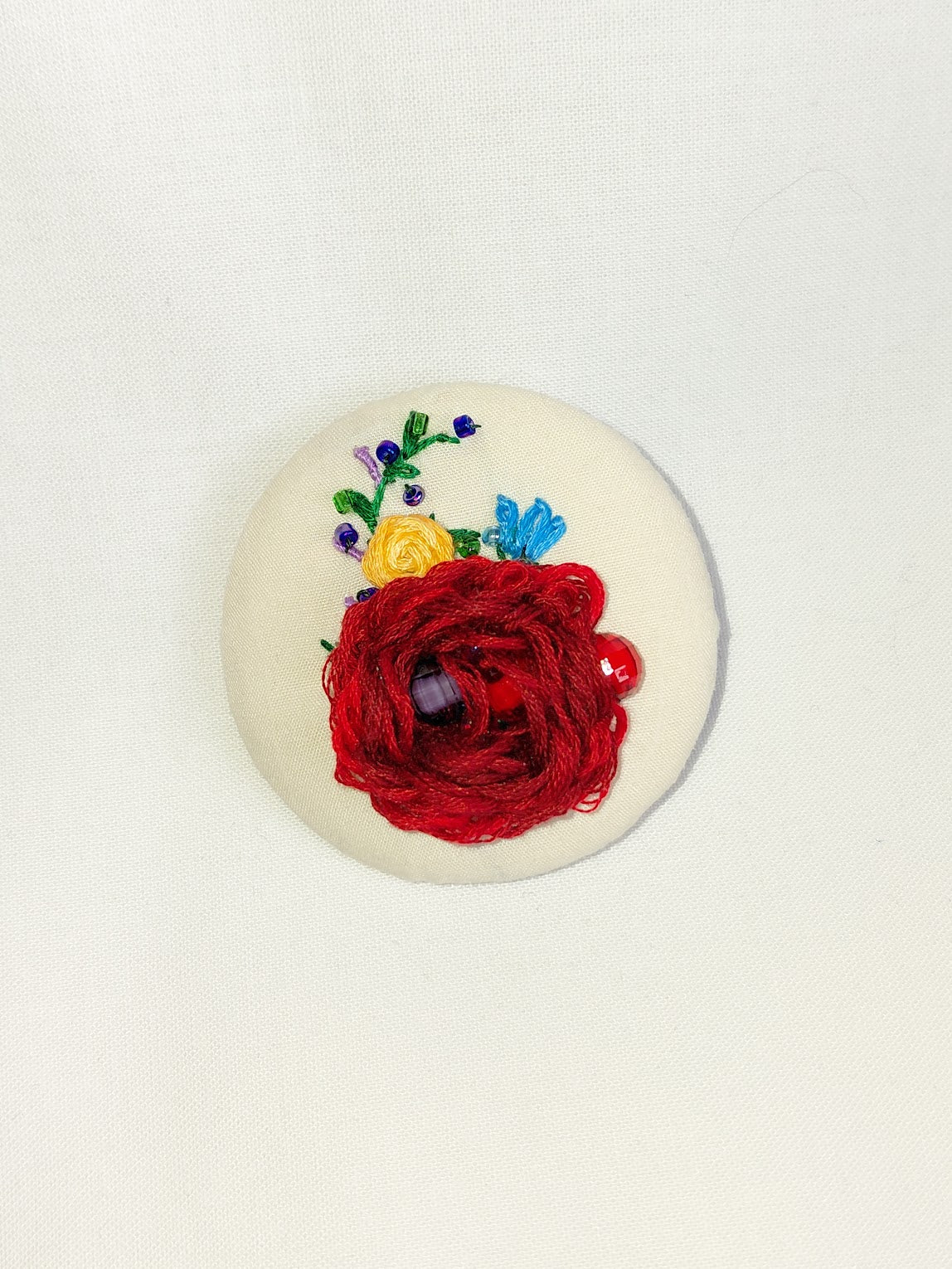 Decorative burgundy flower brooch on cream background