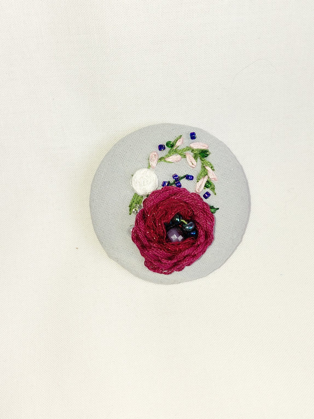 Decorative burgundy flower brooch on blue spec background