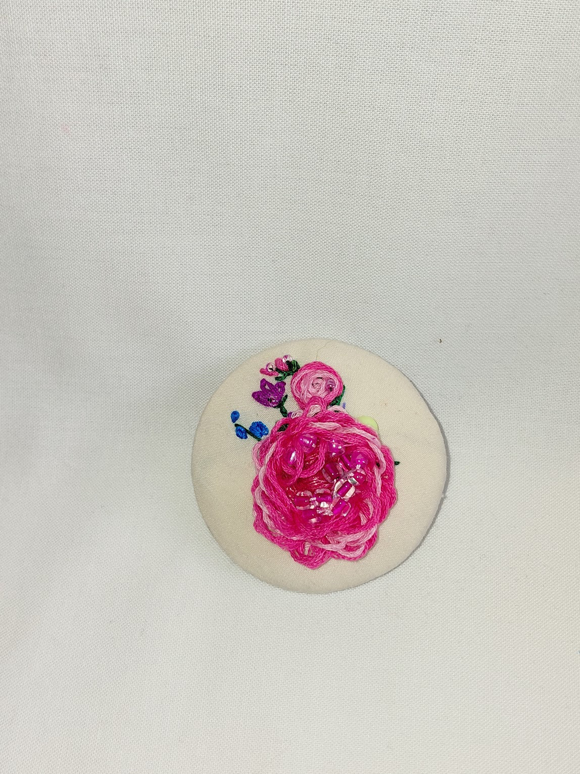 Decorative pink flower brooch on cream background