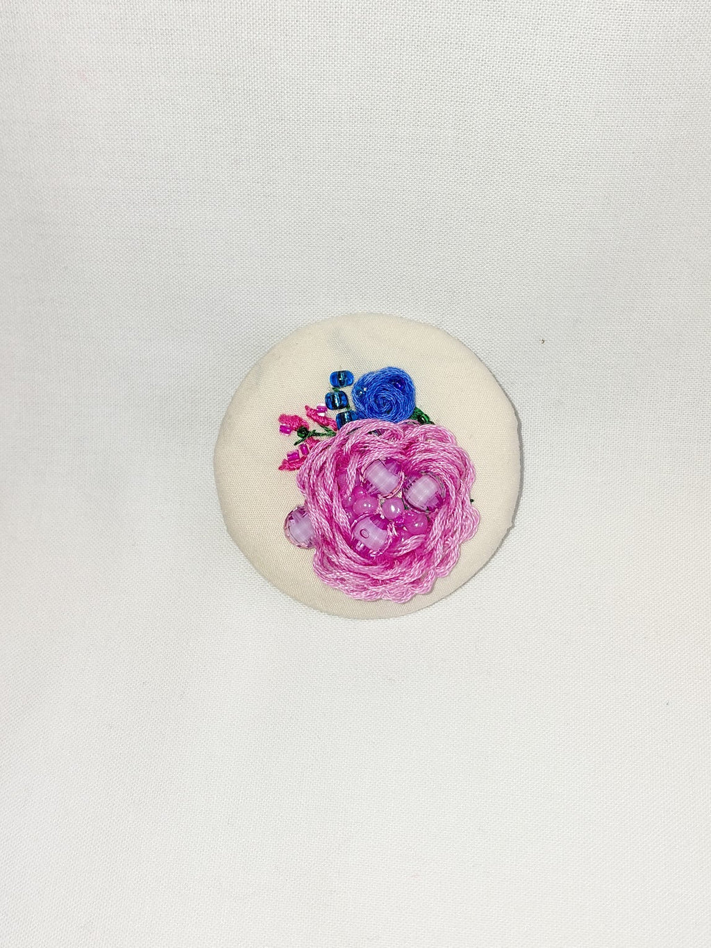 Decorative pink flower brooch on cream background