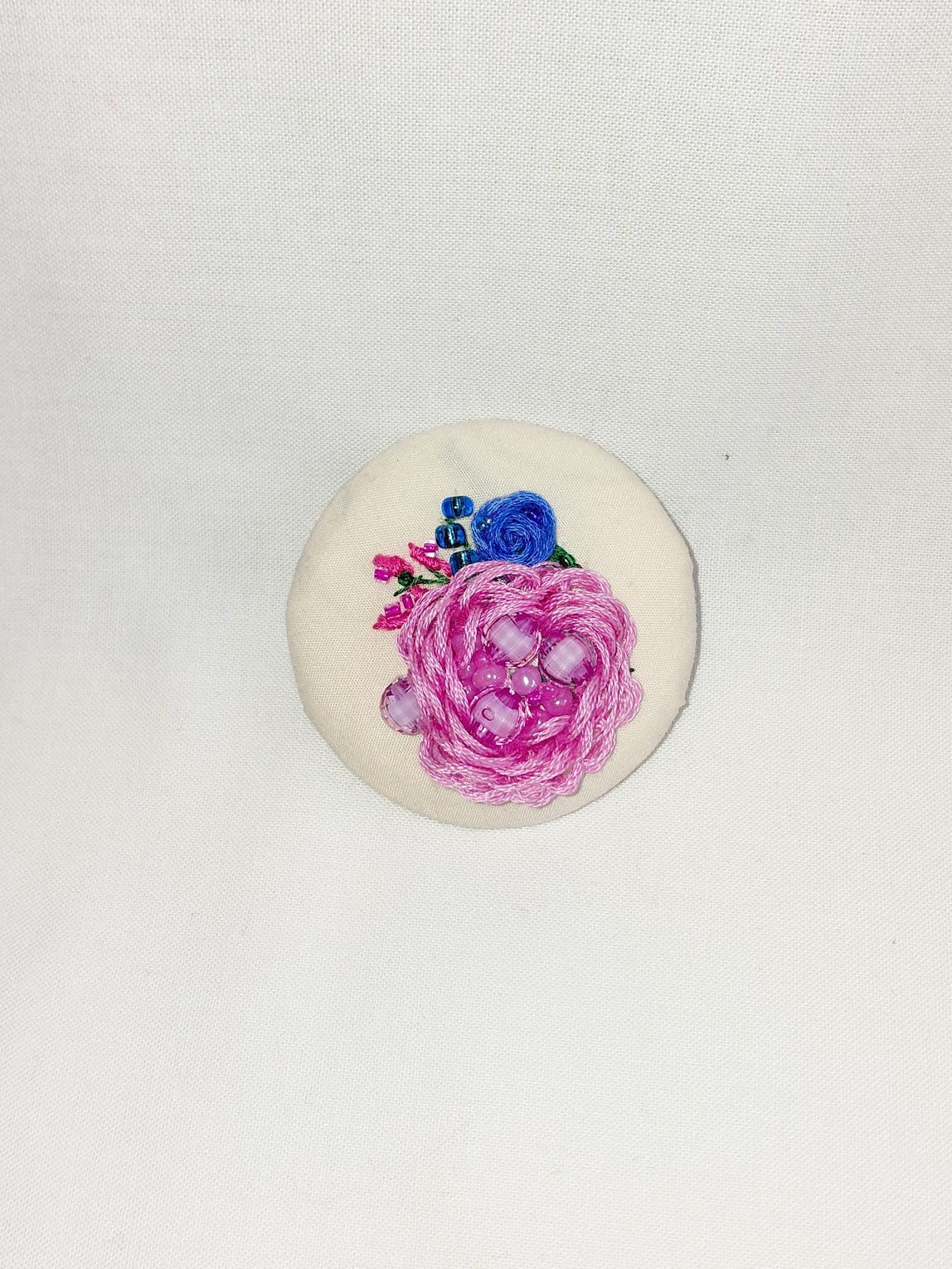 Decorative pink flower brooch on cream background