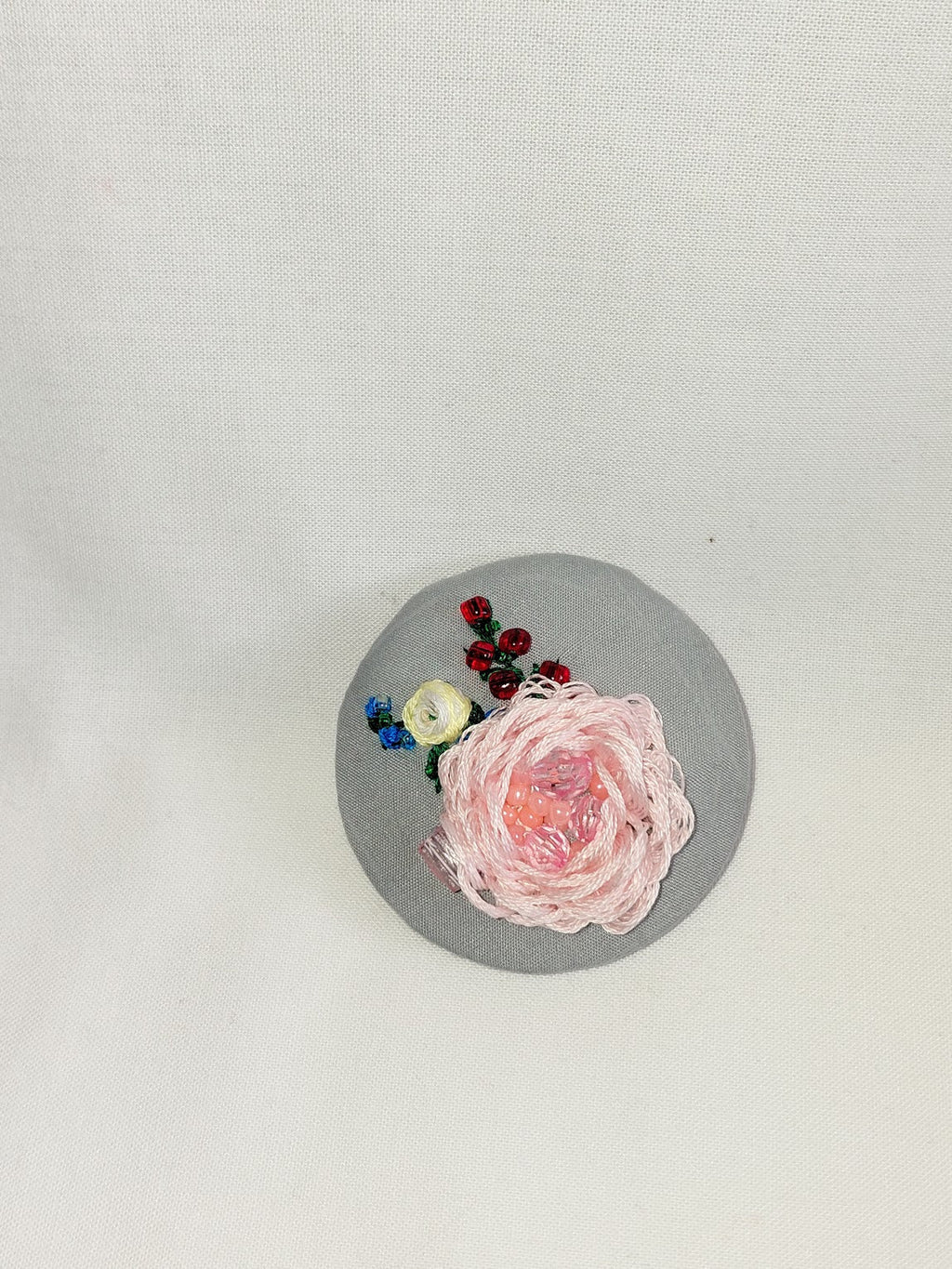 Decorative pink flower brooch on grey background