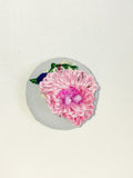 Decorative pink flower brooch on blue spec background