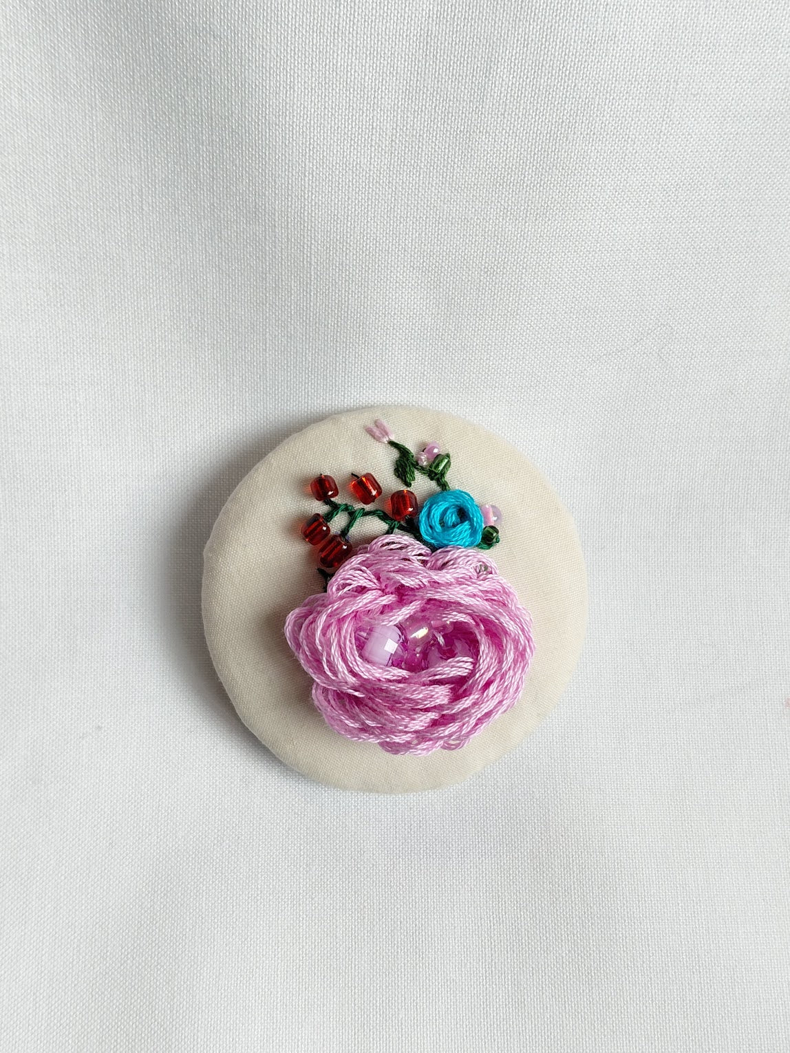 Decorative pink flower brooch on cream background