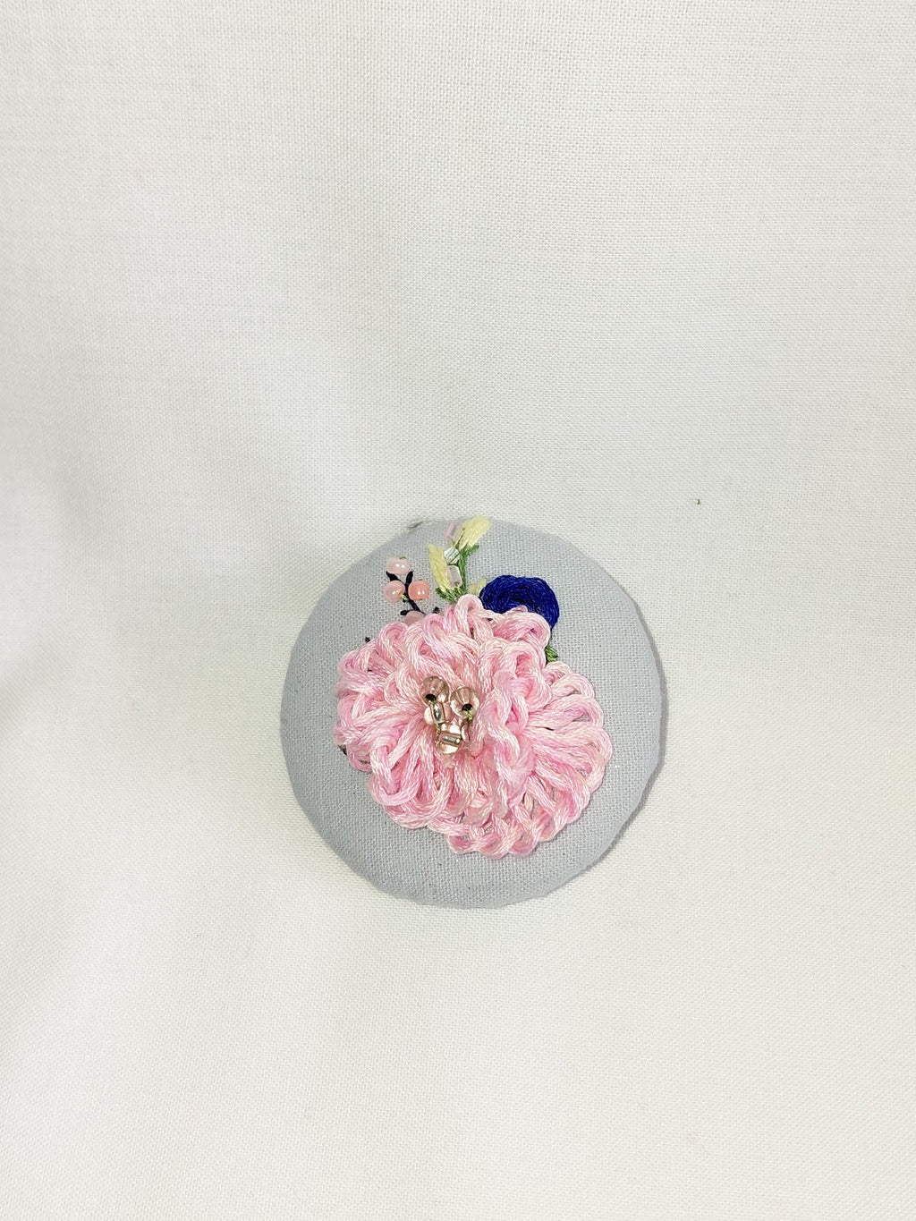 Decorative pink flower brooch on blue spec background