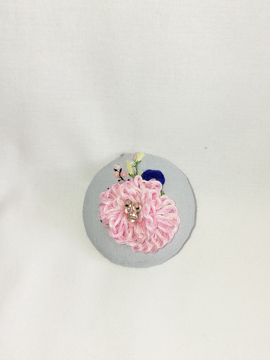 Decorative pink flower brooch on blue spec background