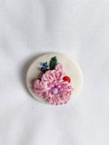 Decorative pink flower brooch on cream background