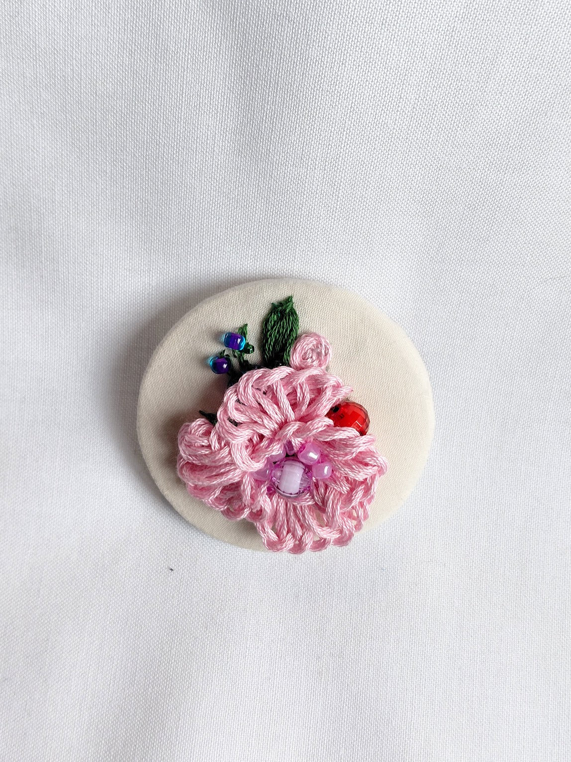 Decorative pink flower brooch on cream background