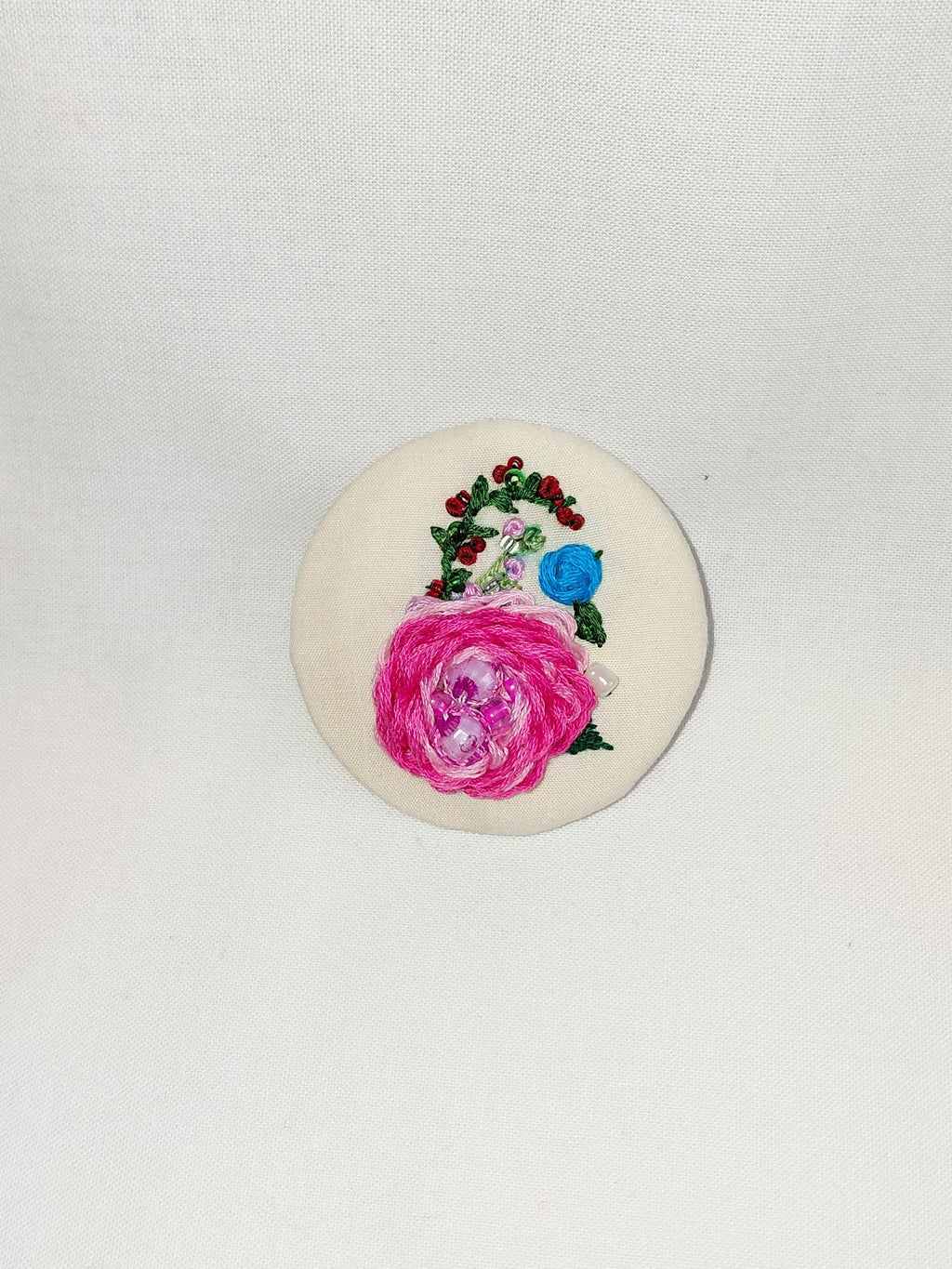 Decorative pink flower brooch on cream background