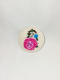 Decorative pink flower brooch on cream background