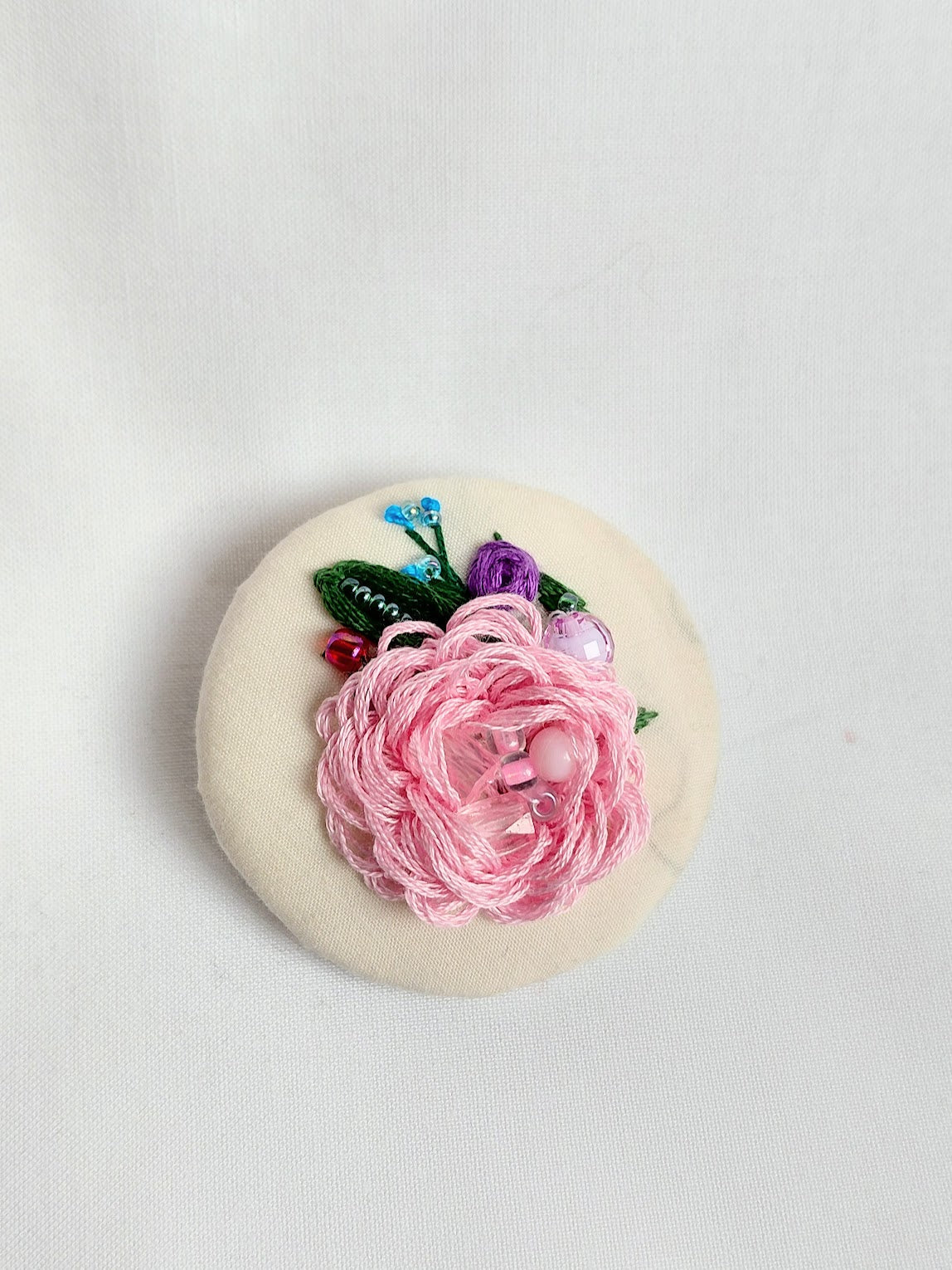 Decorative pink flower brooch on cream background