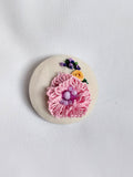 Decorative pink flower brooch on cream background